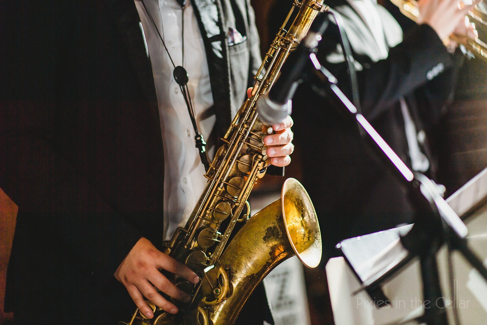 Person playing a gold-colored alto saxophone with sheet music stand in the background.