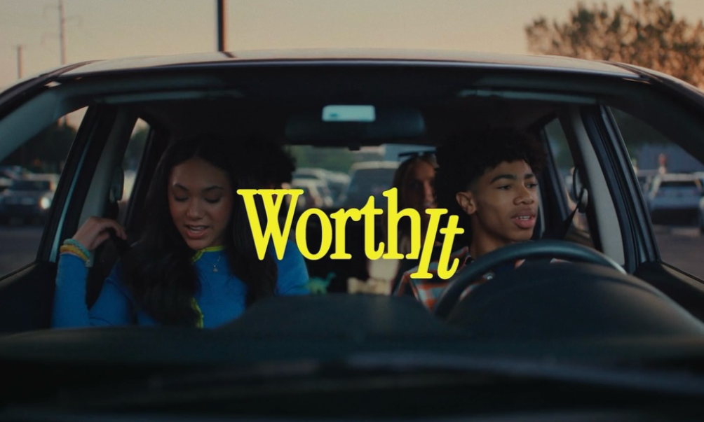 Several people sitting in a car, with the word 'Worthy' overlayed in yellow text.