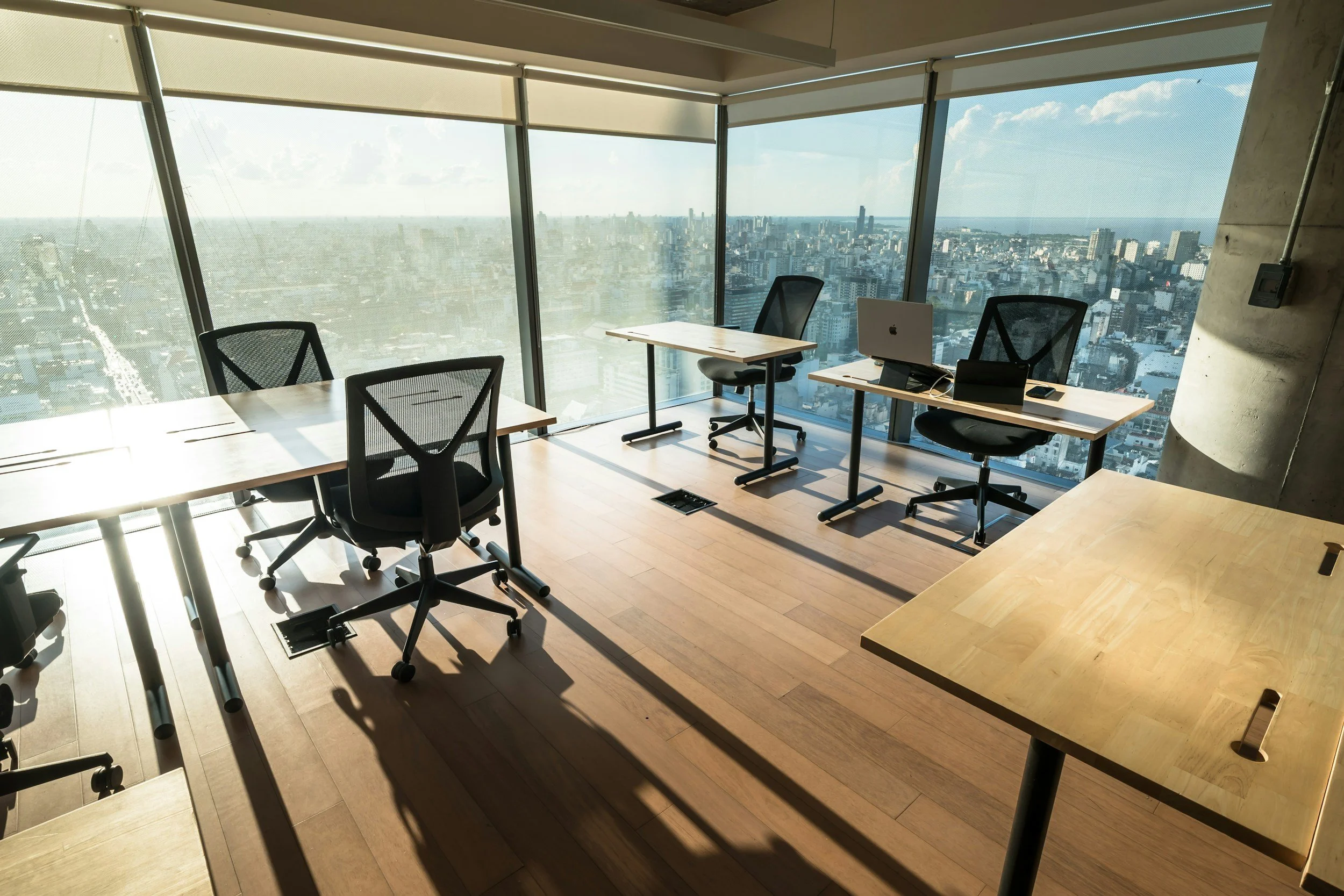 Oficina moderna con escritorios y ventanales de piso a techo con vista a la ciudad