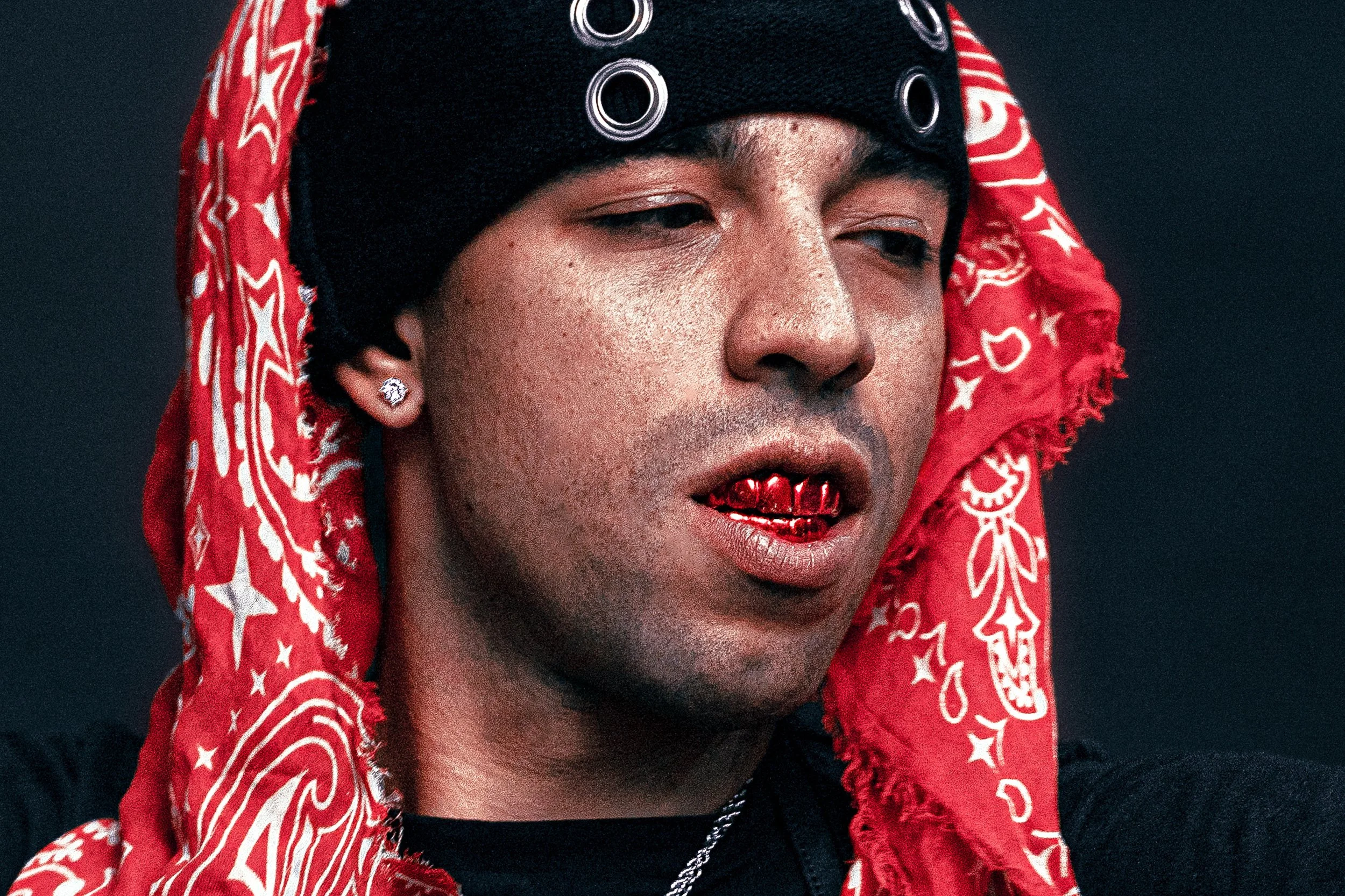 Close-up portrait of a man wearing a red bandana and black headwear. FOURFIVE