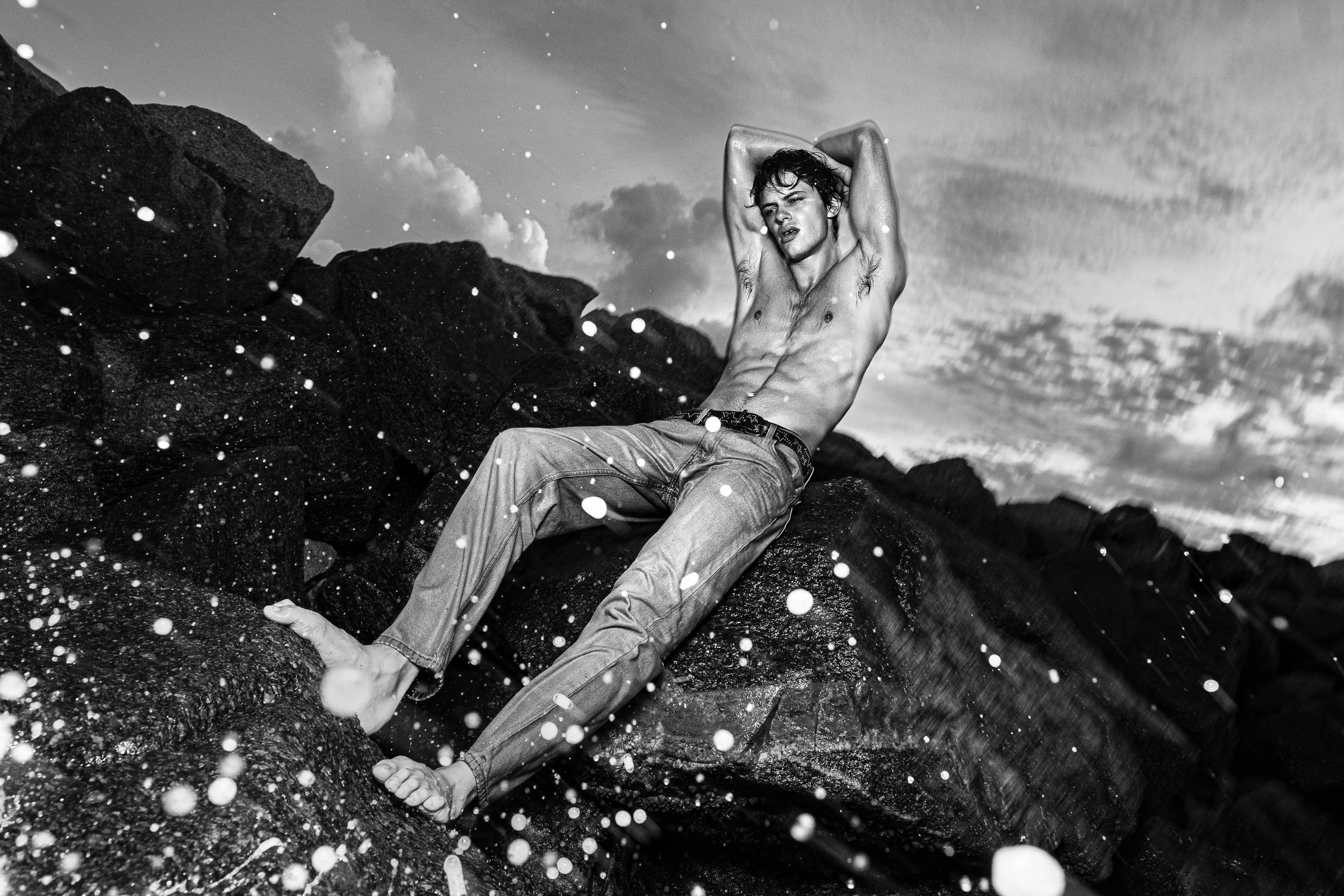 Black-and-white fashion portrait reclining among rocks and splashing water. NILS EMIL BREMER