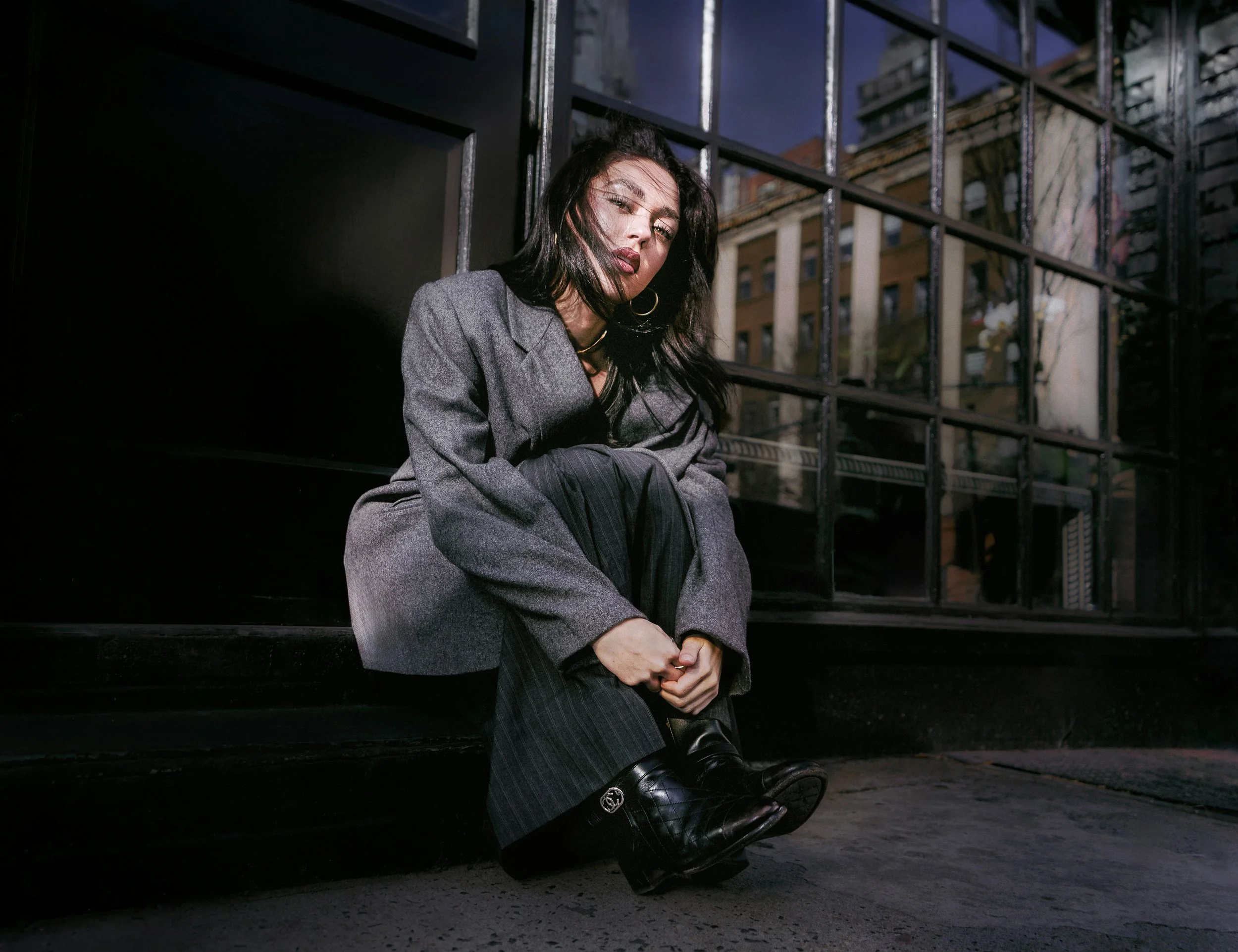 Outdoor fashion portrait of a model crouching in an urban setting. AMAILIA QUILES 