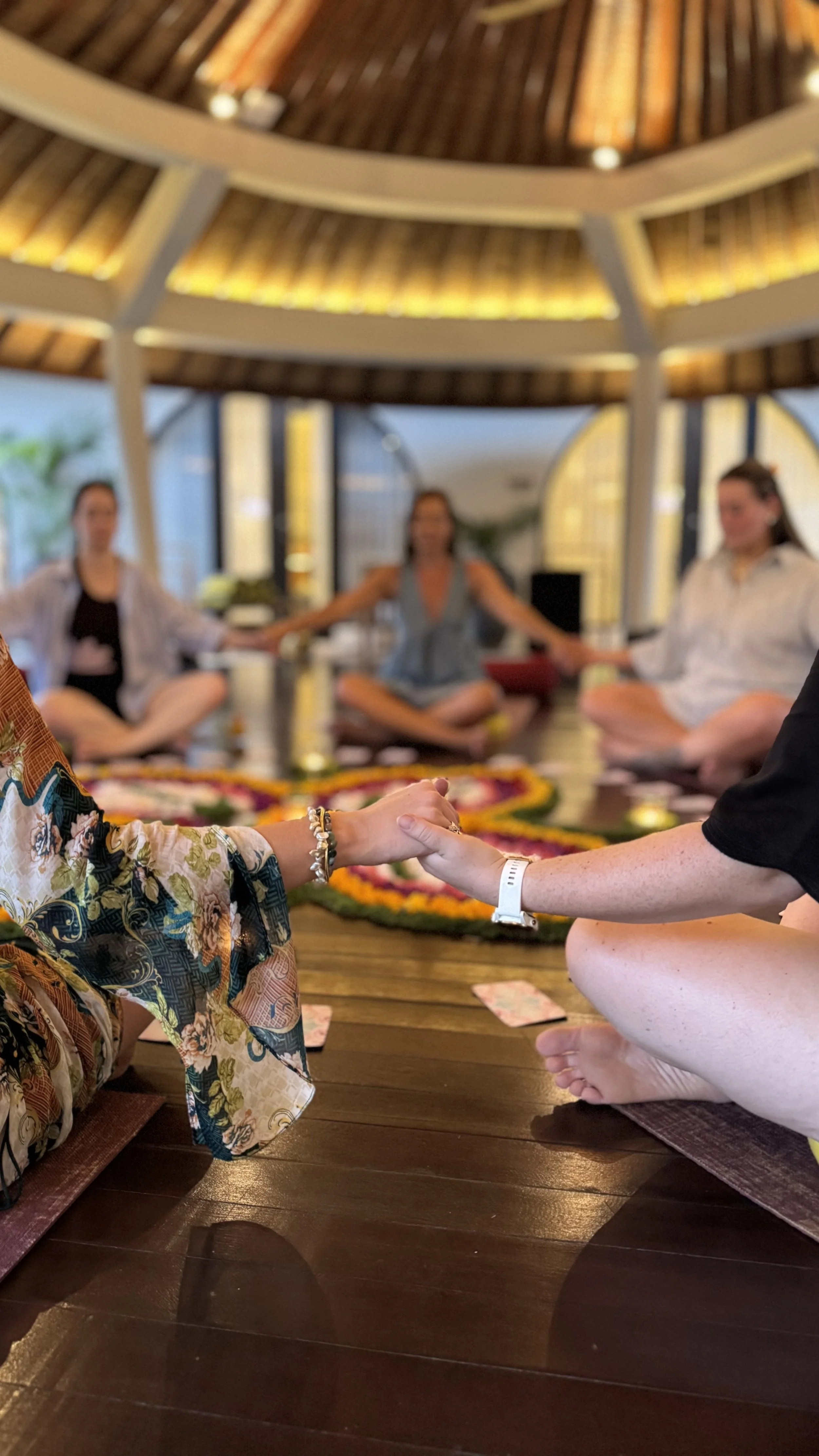 Blurry group of people holding hands around a colorful table in a warmly lit indoor setting
