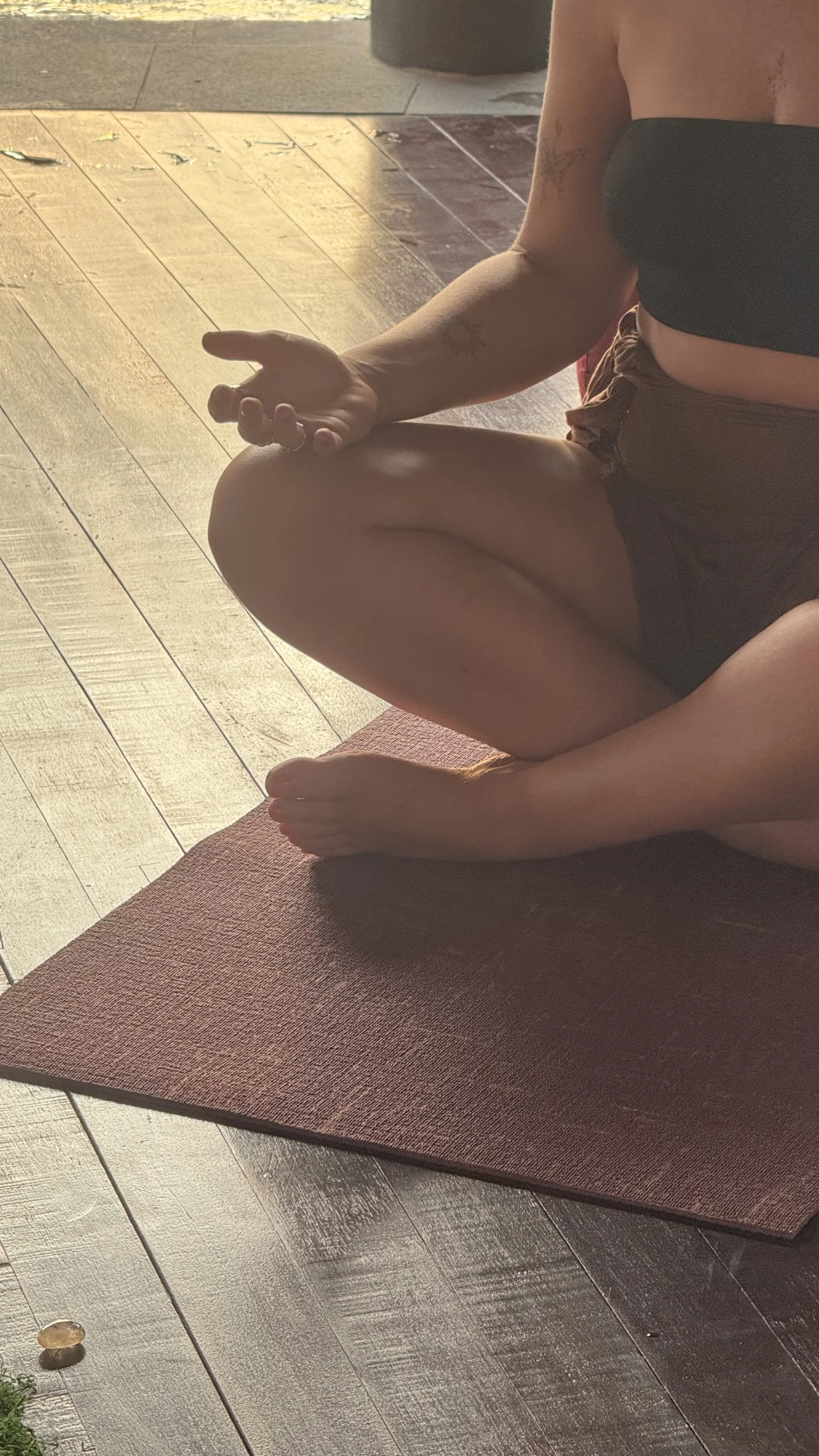Person sitting cross-legged on a yoga mat with palms facing upward in a meditative pose