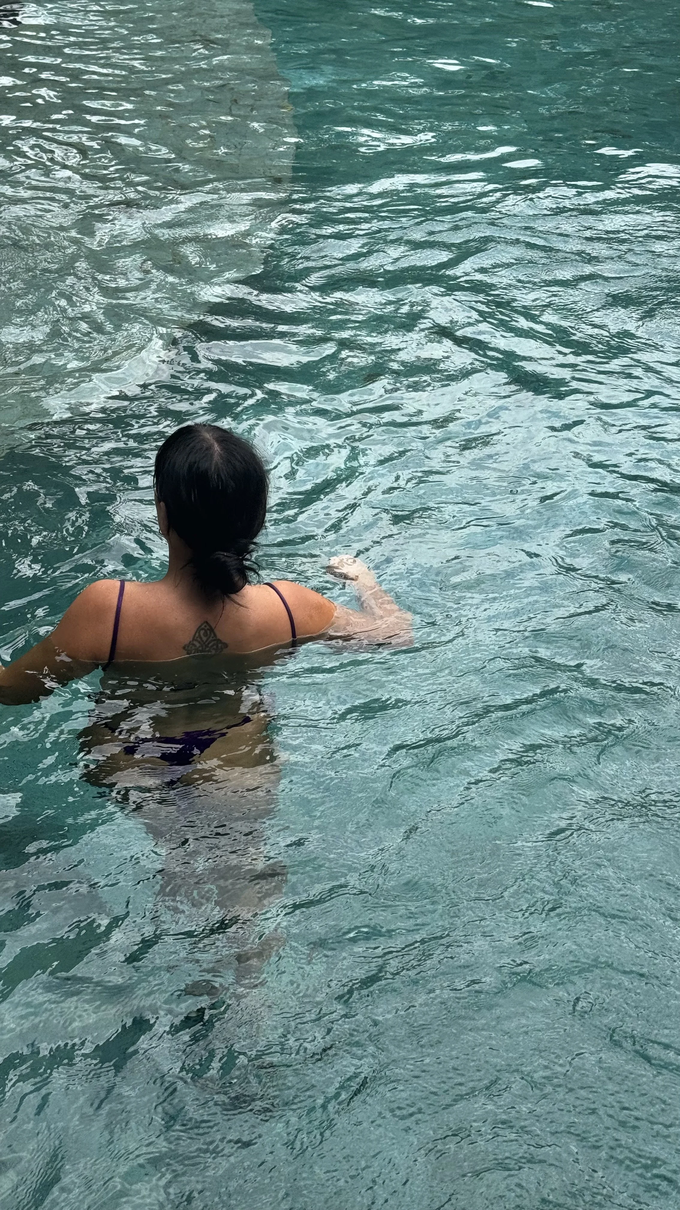 Person swimming in a turquoise pool with rippling water