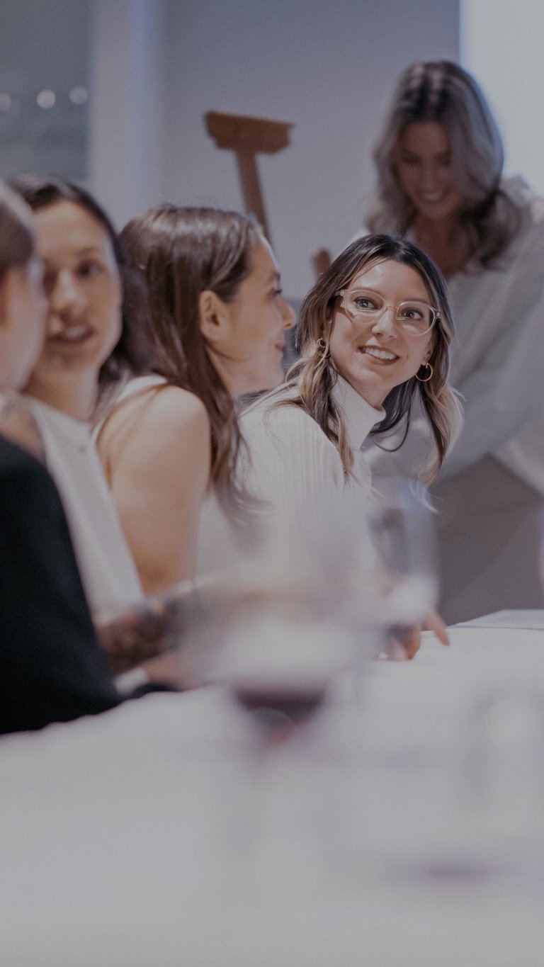 Group of women smiling and talking around a table during a social gathering