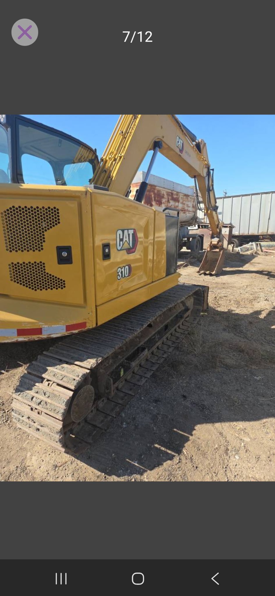 Yellow Caterpillar excavator parked on dirt ground at a construction site.