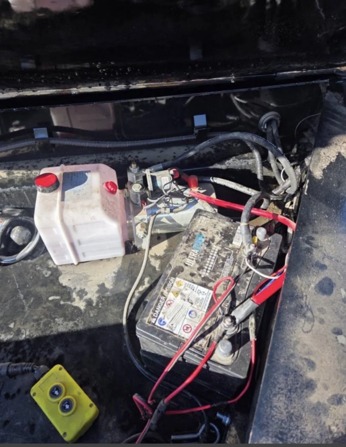 2026 ED dump trailer, close-up of hydraulic pump, battery, wiring, and trailer components.