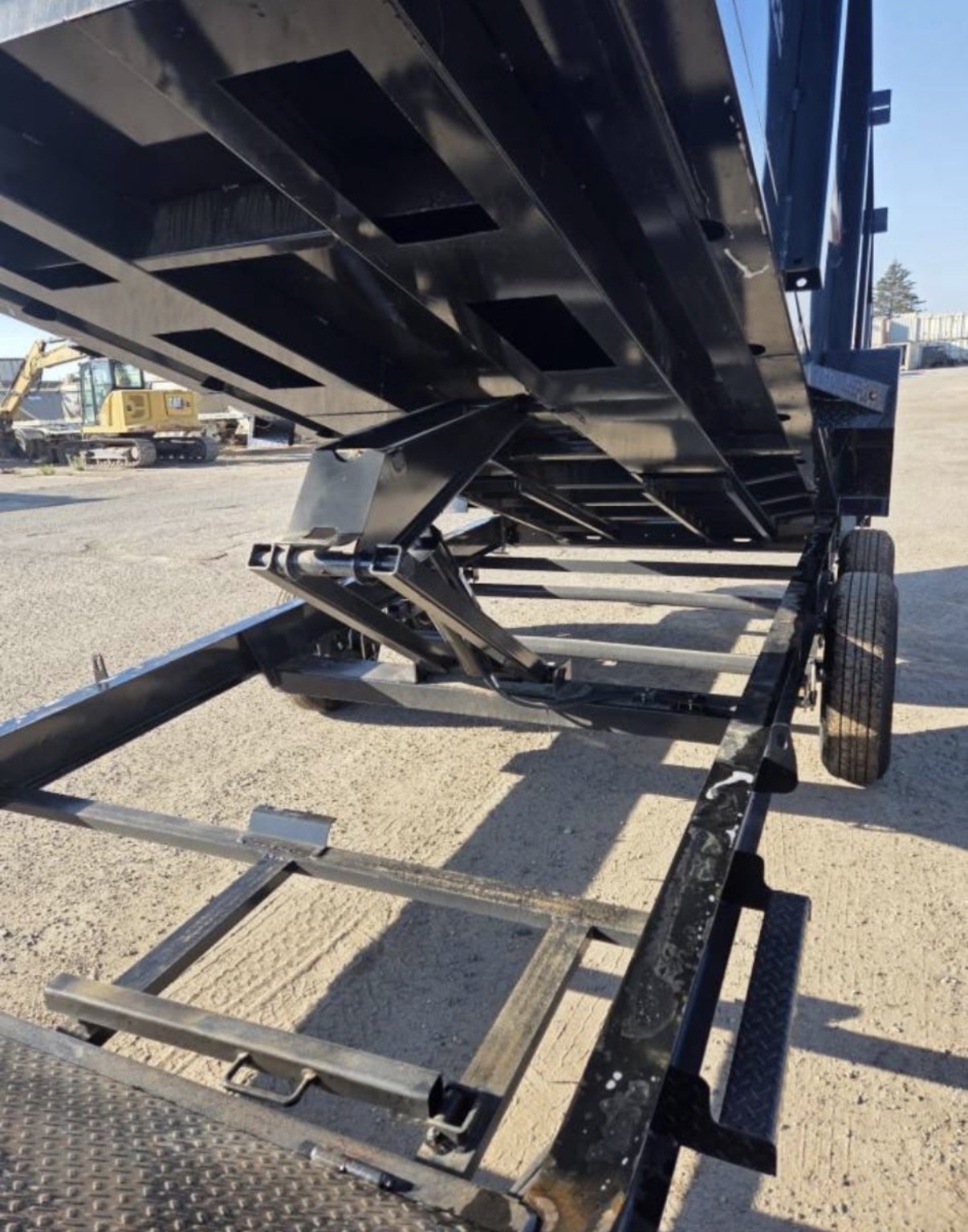 A black flatbed trailer with a hydraulic lift system