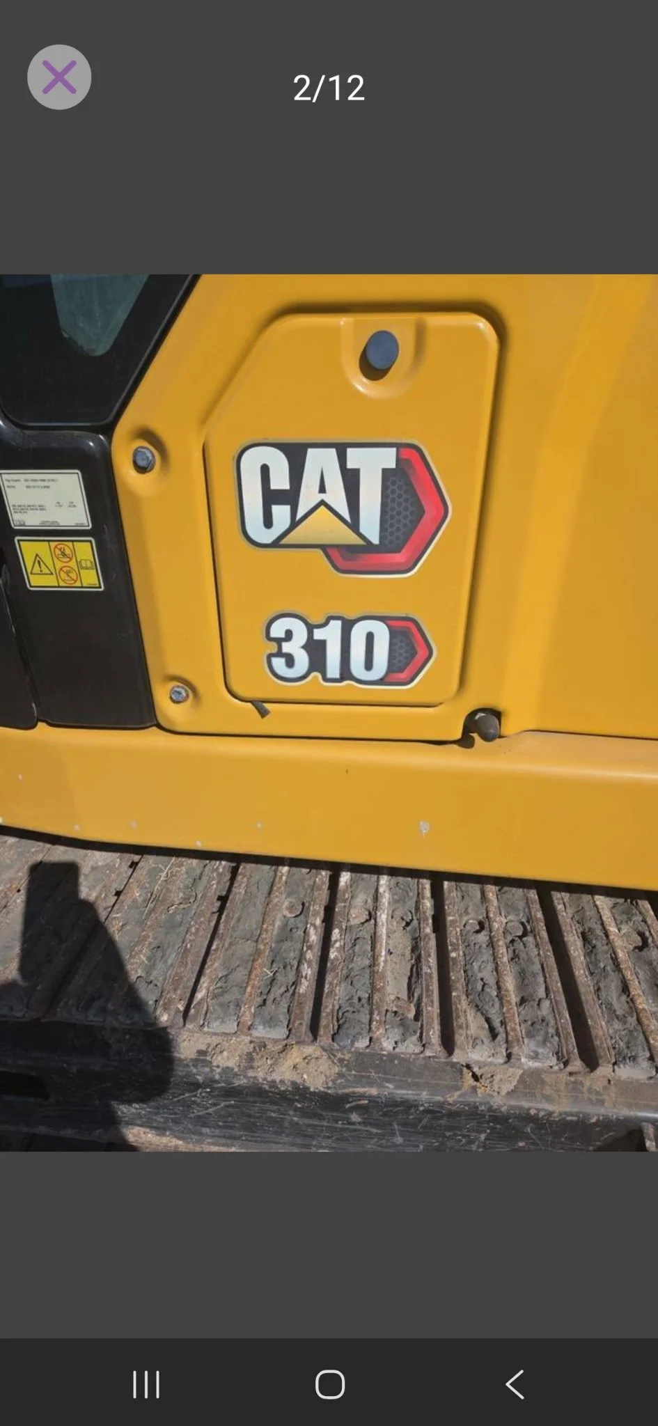 Close-up of a yellow Caterpillar 310 construction equipment with the CAT logo and model number on the side.