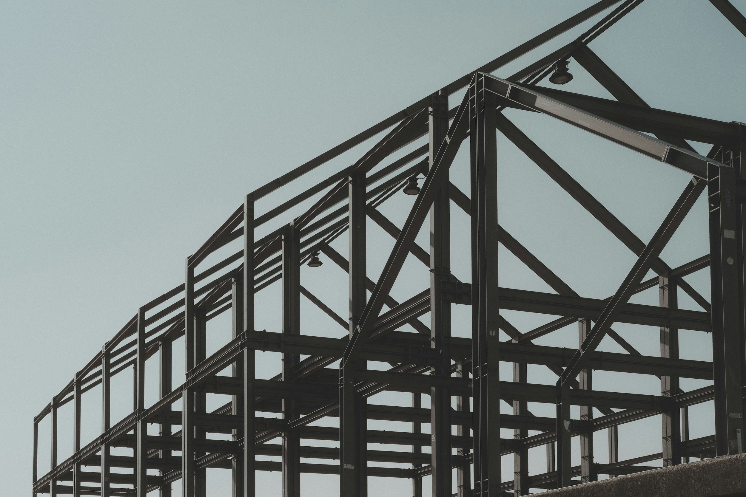 A steel framework structure of a building under construction against a pale sky.