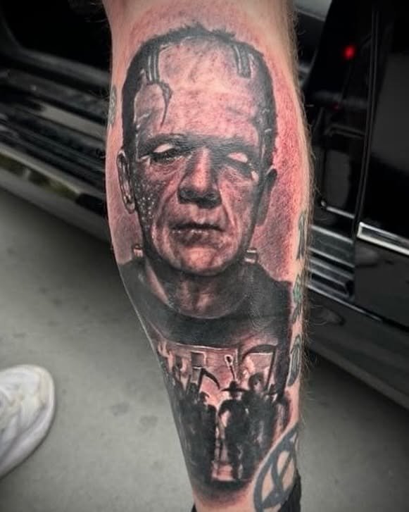 Tattoo of Frankenstein's monster with a distorted face and a figure in the background.