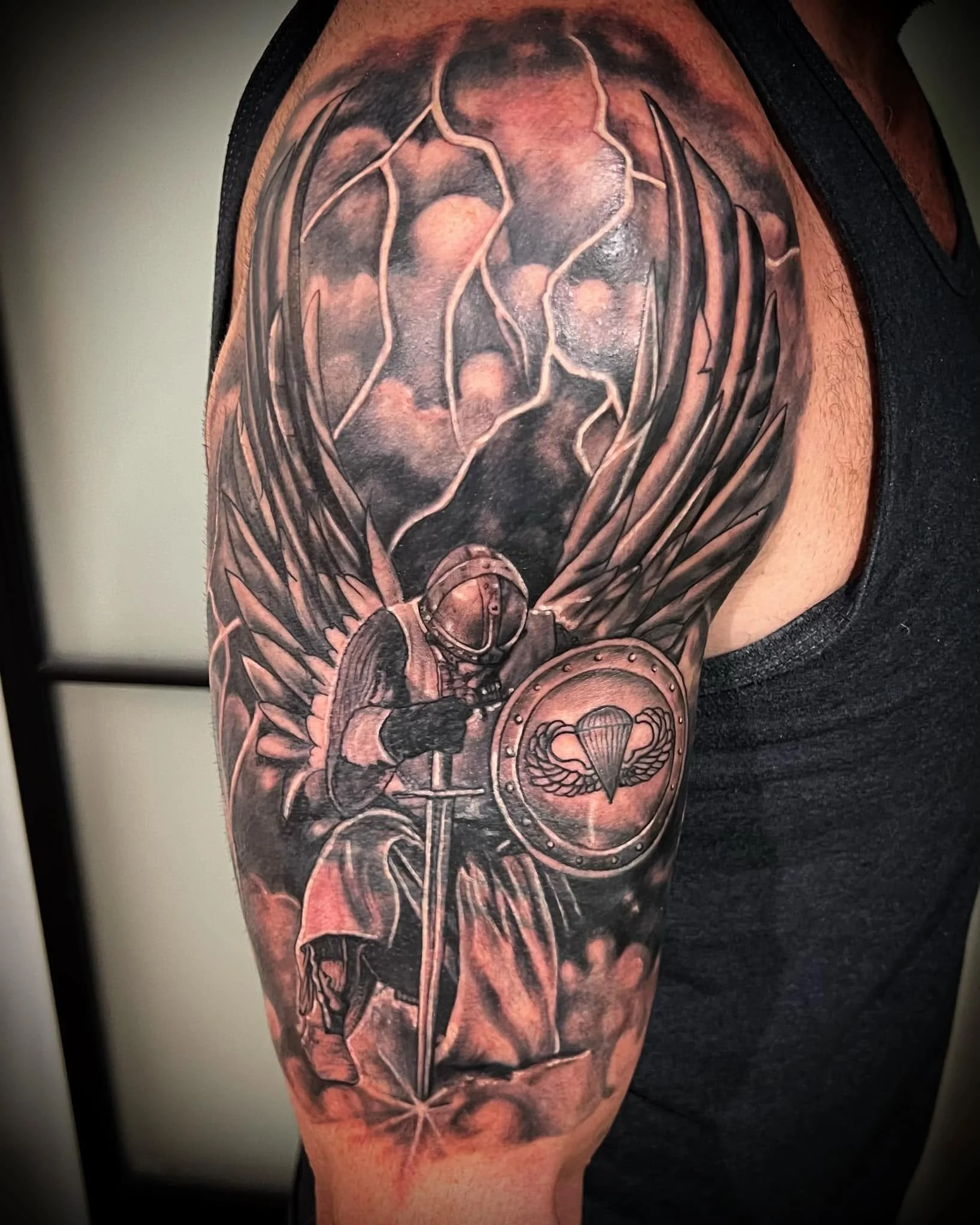 Black and gray tattoo on a person's upper arm and shoulder, featuring a skull, celestial elements, and abstract designs.