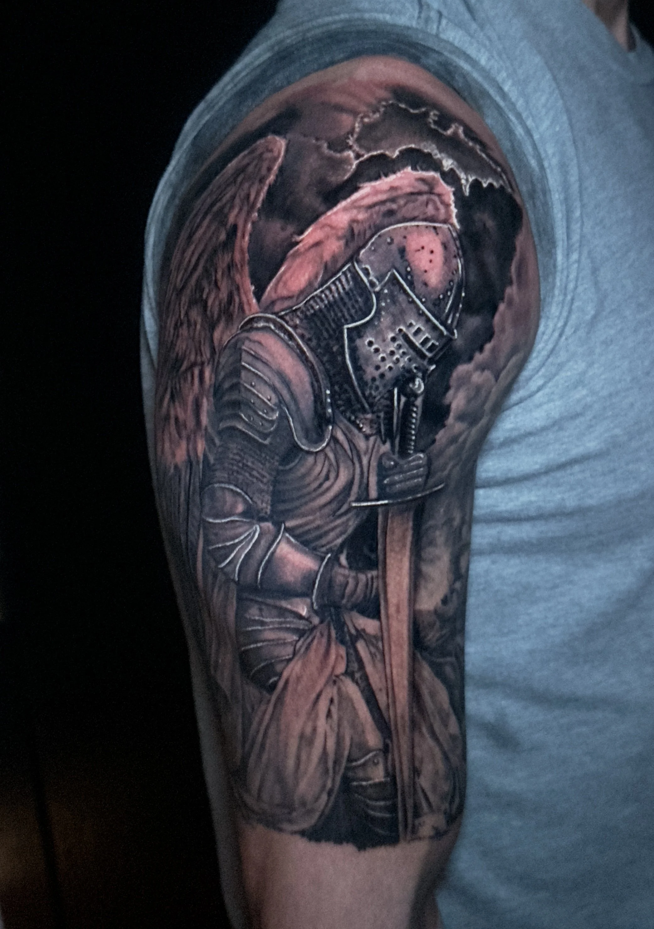 Tattoo of a soldier's face wearing a helmet and gas mask on upper arm.