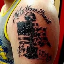 Tattoo of a microphone with the text 'Make Them Proud' above and 'John 15:13' below on a person's shoulder.
