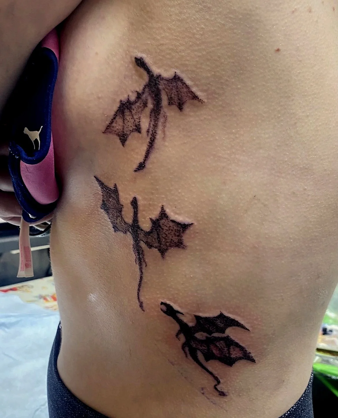 Close-up of a person's side torso with a black bat-shaped tattoo.