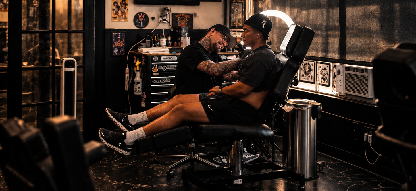 Tattoo artist in a black t-shirt and cap tattooing a person's leg in a tattoo shop
