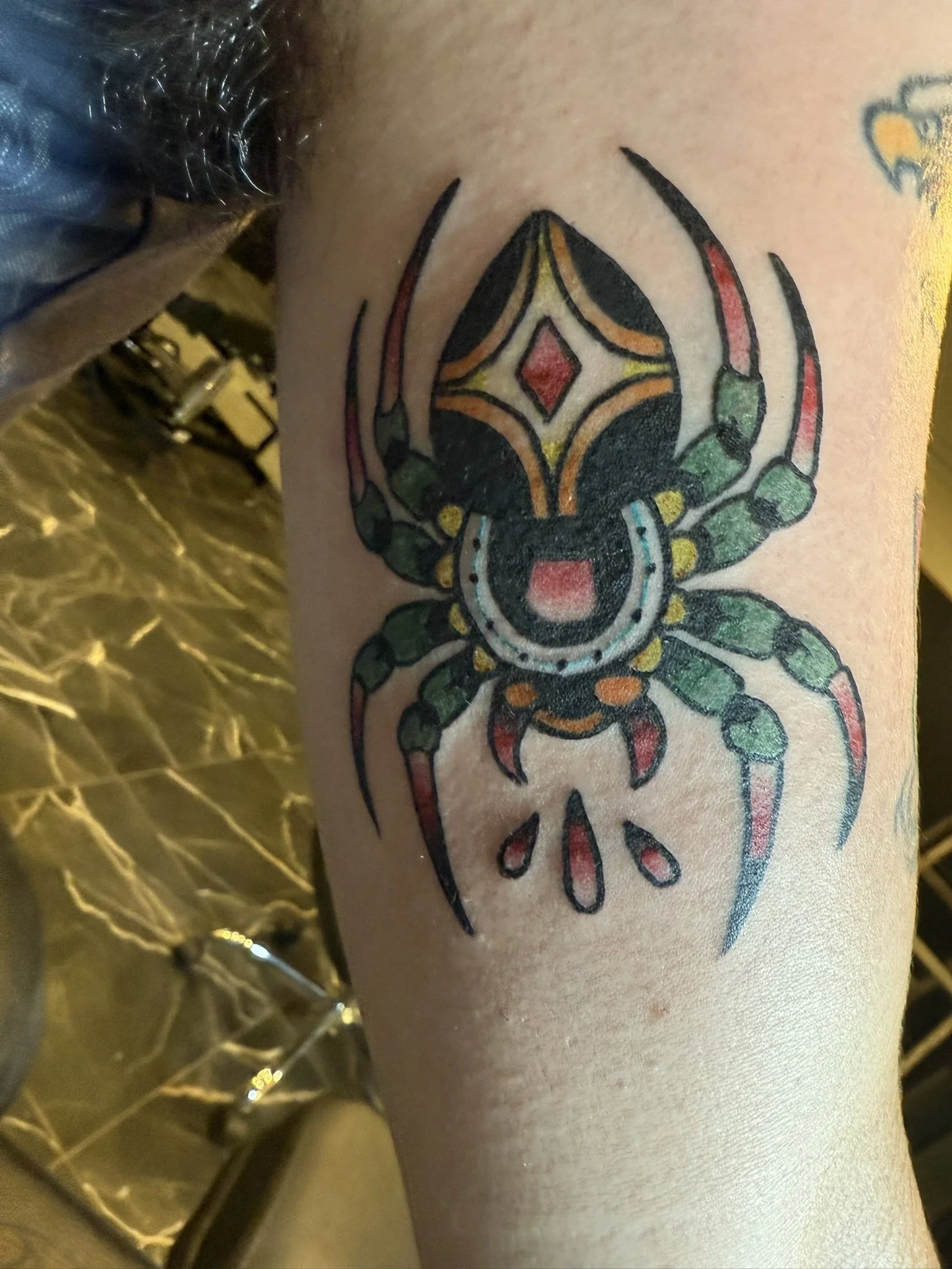 Close-up of a colorful tattoo of a spider on a person's skin.