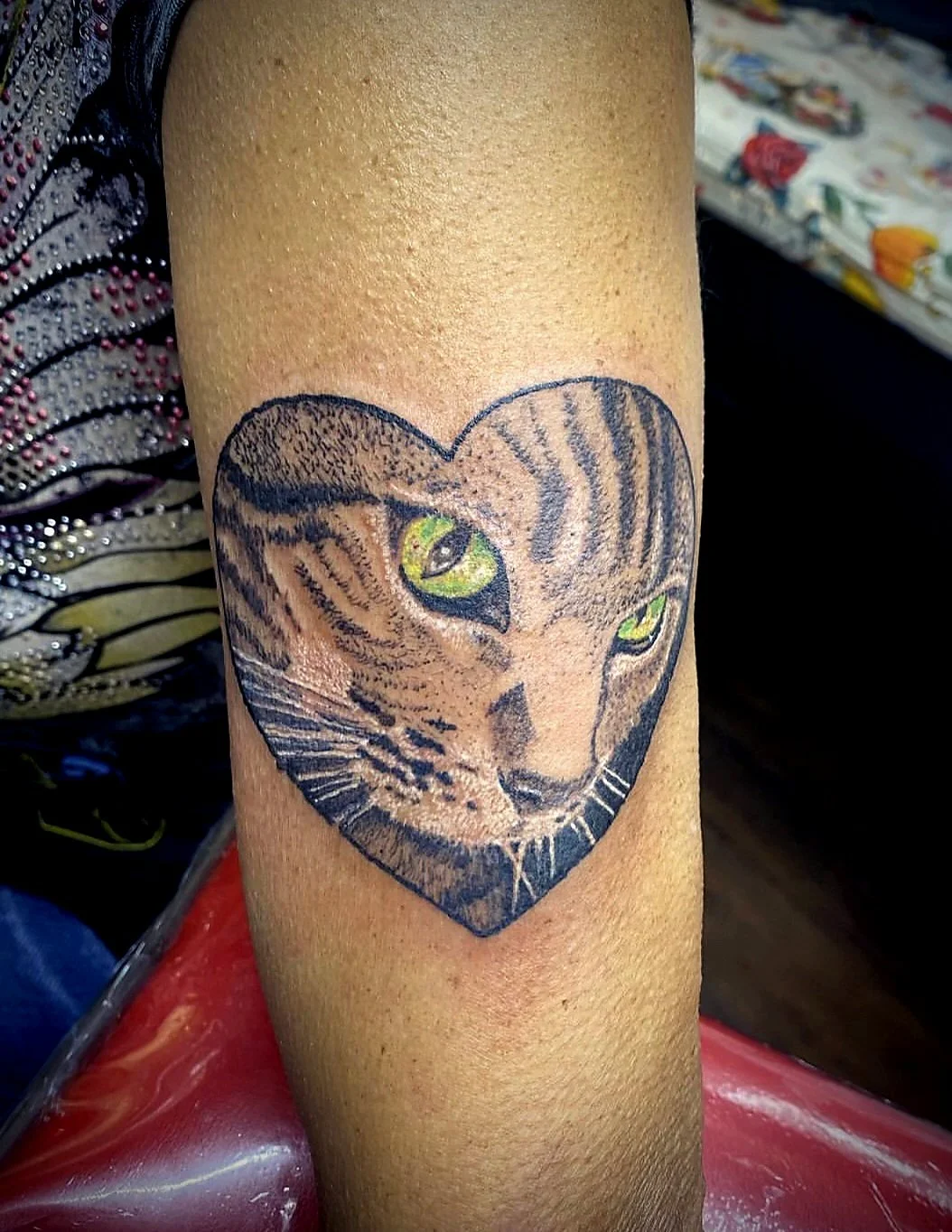 Tattoo of a tiger's face inside a heart shape on a person's arm.