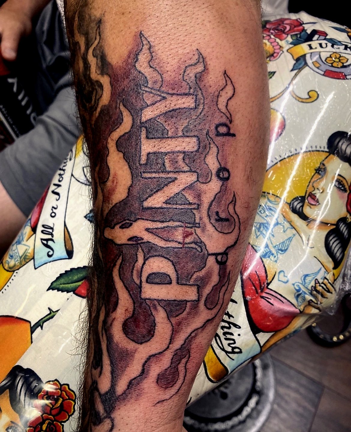 Tattoo of the word 'FUME' with flame and smoke details on a person's arm.