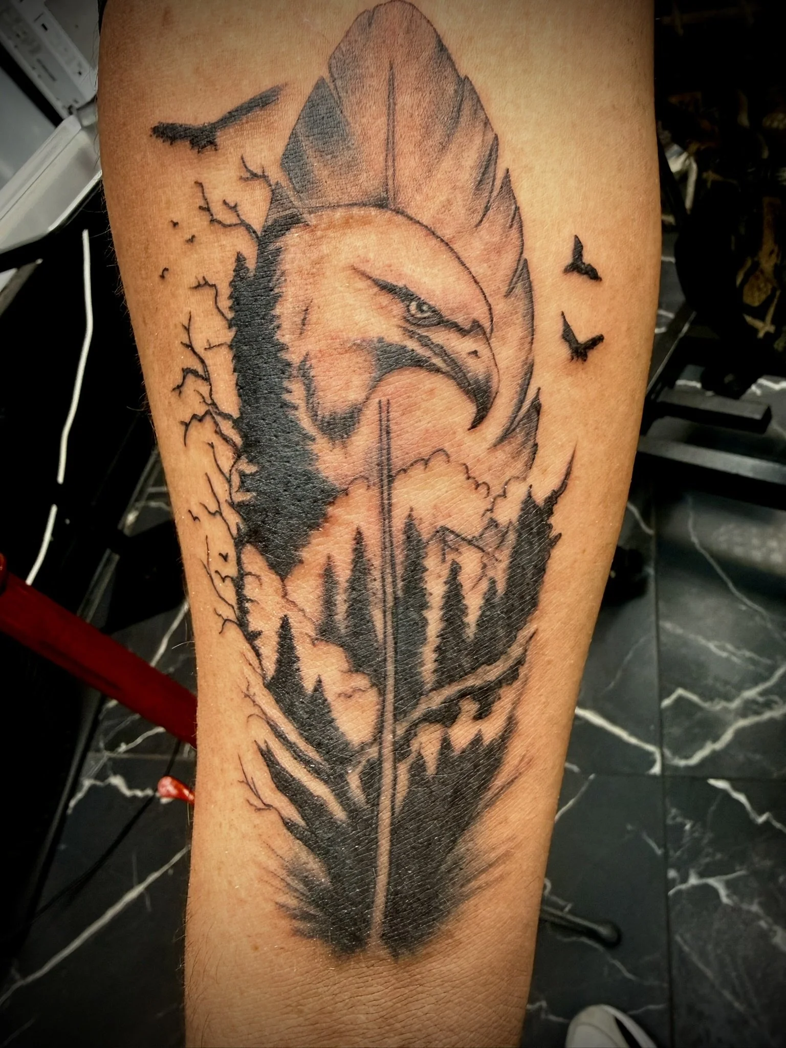 A tattoo of a fierce wolf's head with a snow-coated mountain in the background, along with flying bats and barren trees.