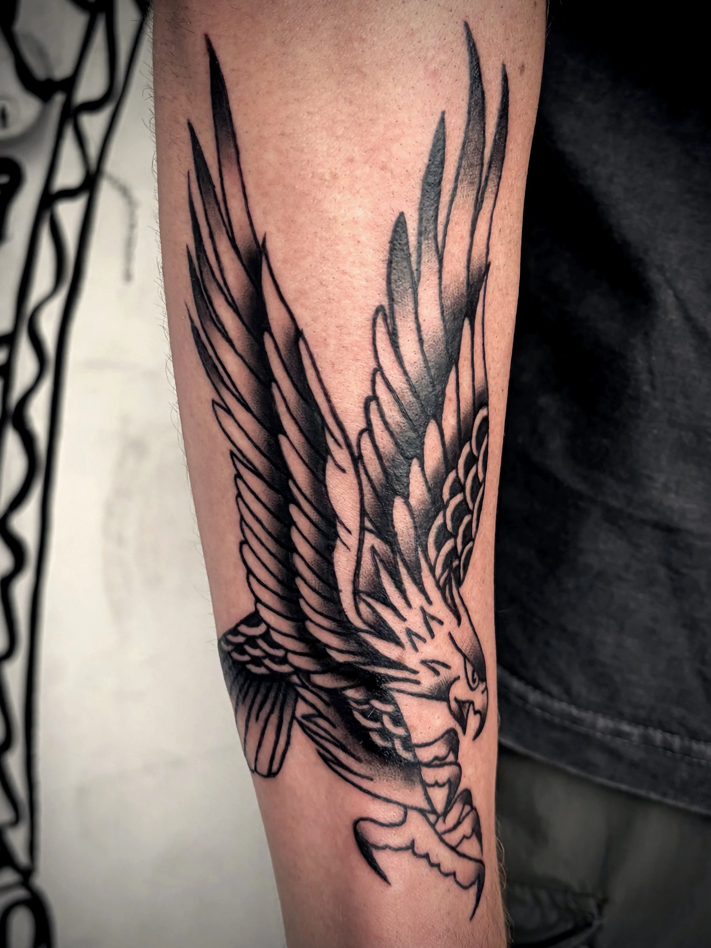 Tattoo of a bird with outstretched wings on a person's forearm.