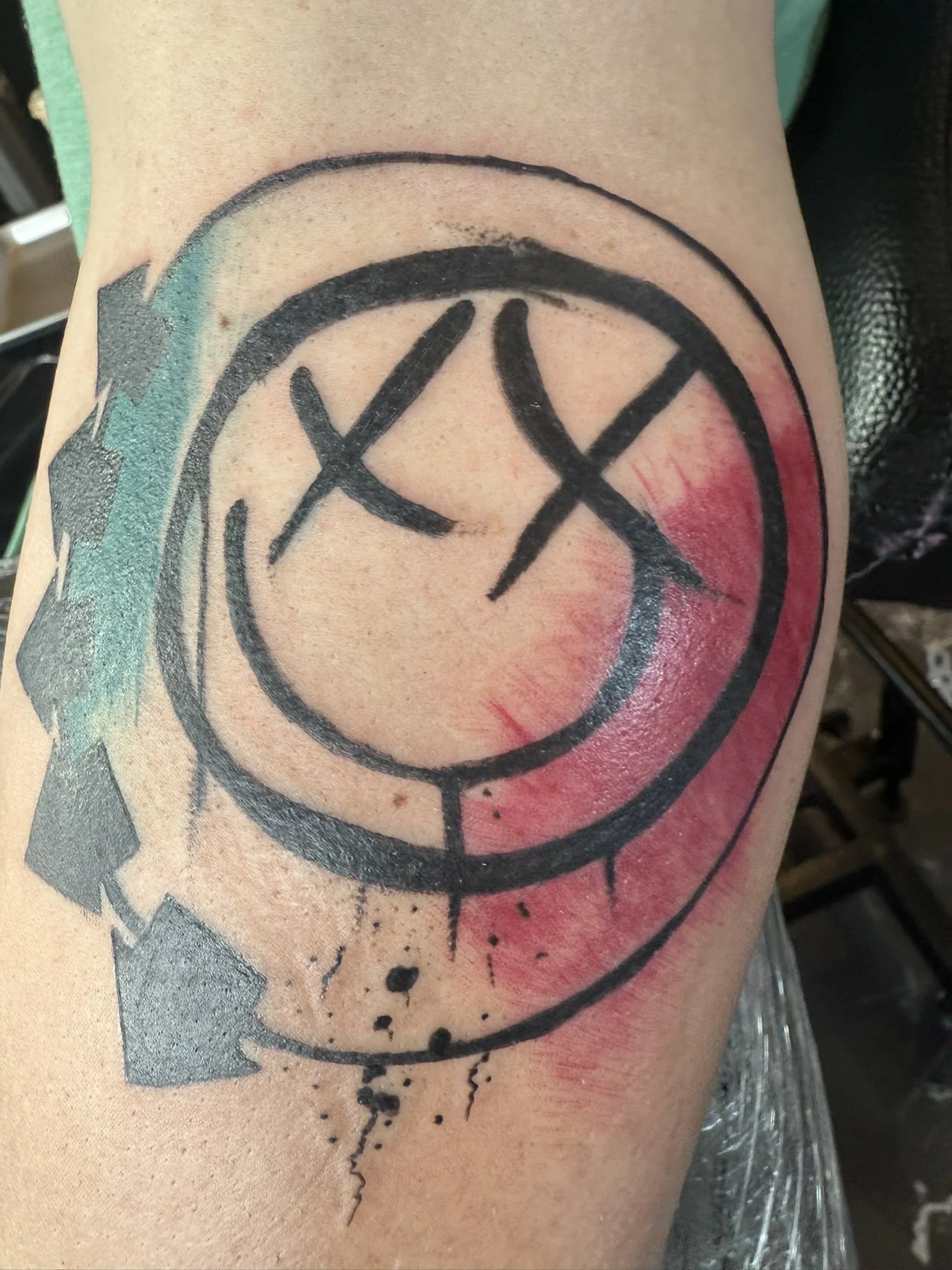 Tattoo of a clock with Roman numerals on the person's arm, with black ink and watercolor style elements.