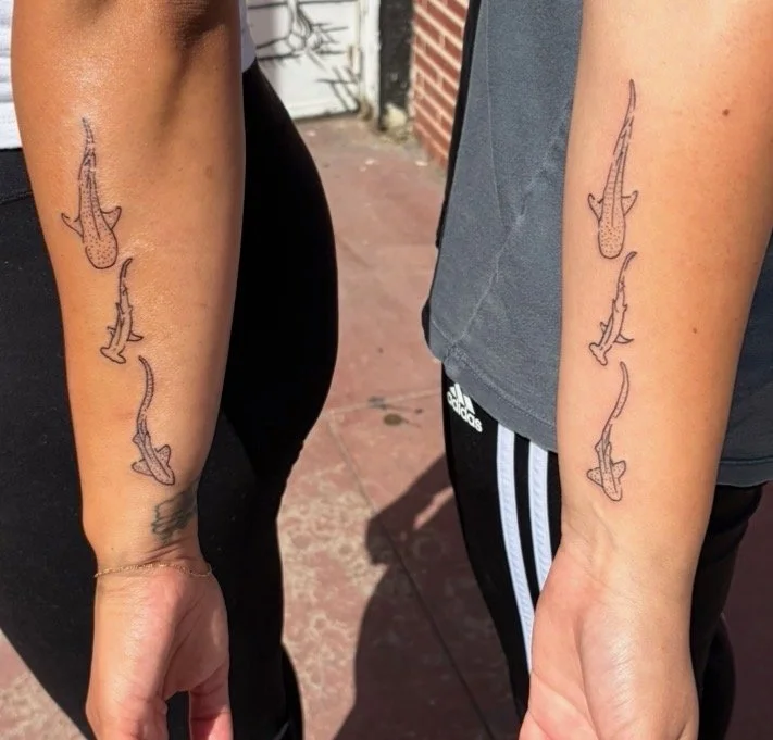 Tattoo of three fish swimming in the same direction on each person's forearm.