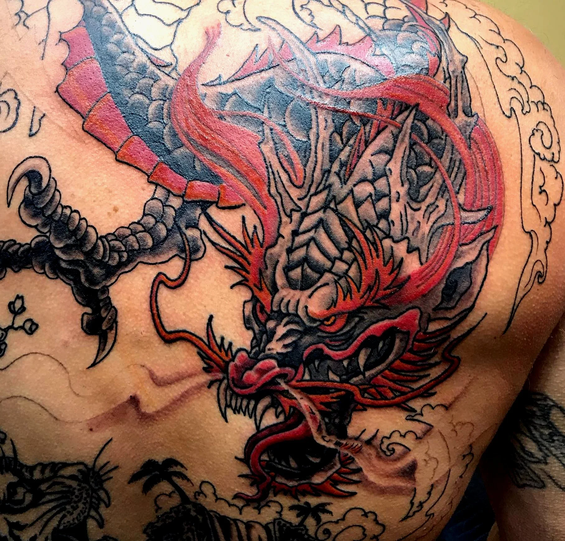 Colorful tattoo of a dragon on person's chest with red and black ink details.