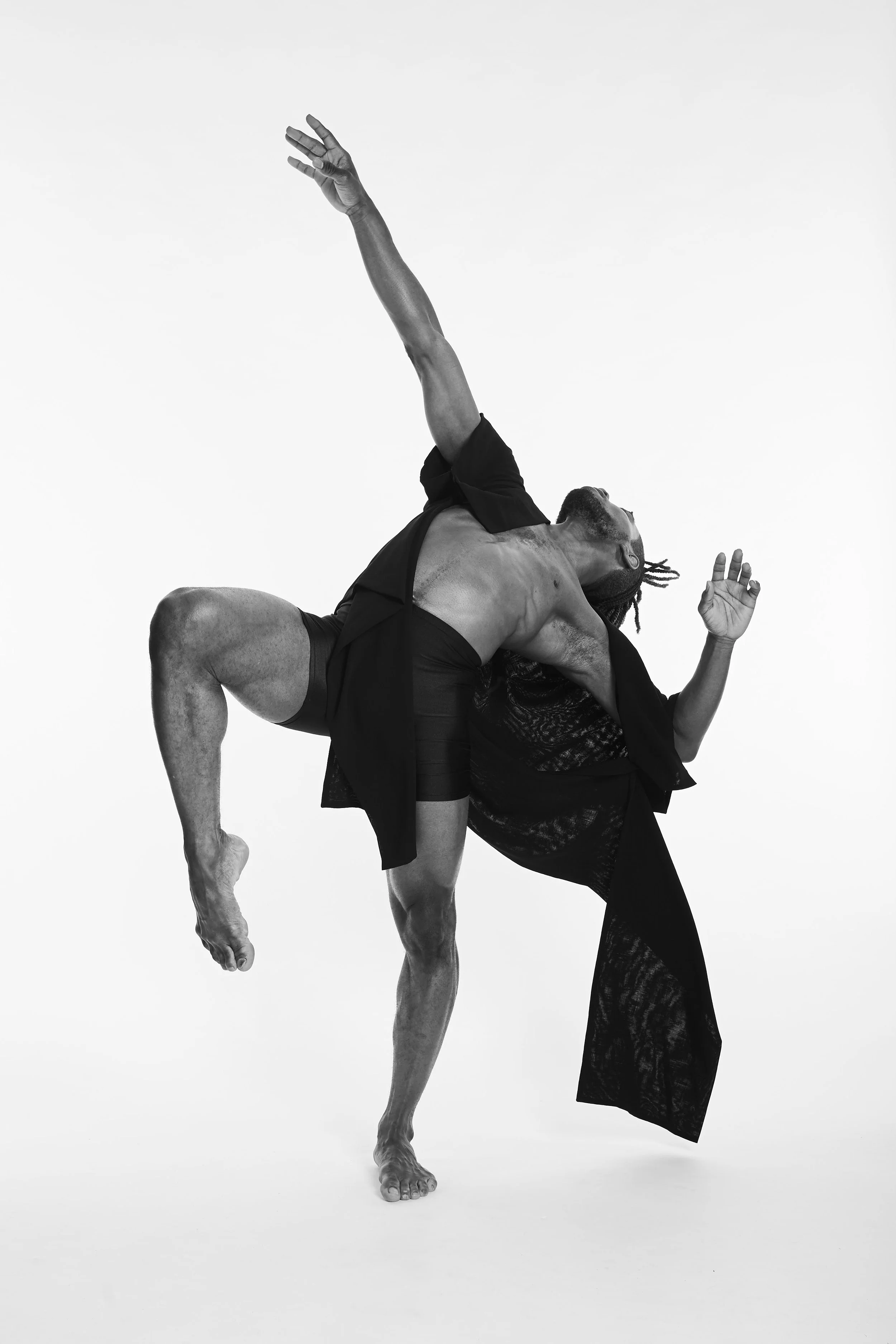 Black and white photo of two people dancing, with one person lifted off the ground and their head and arms extended, while the other person supports them.