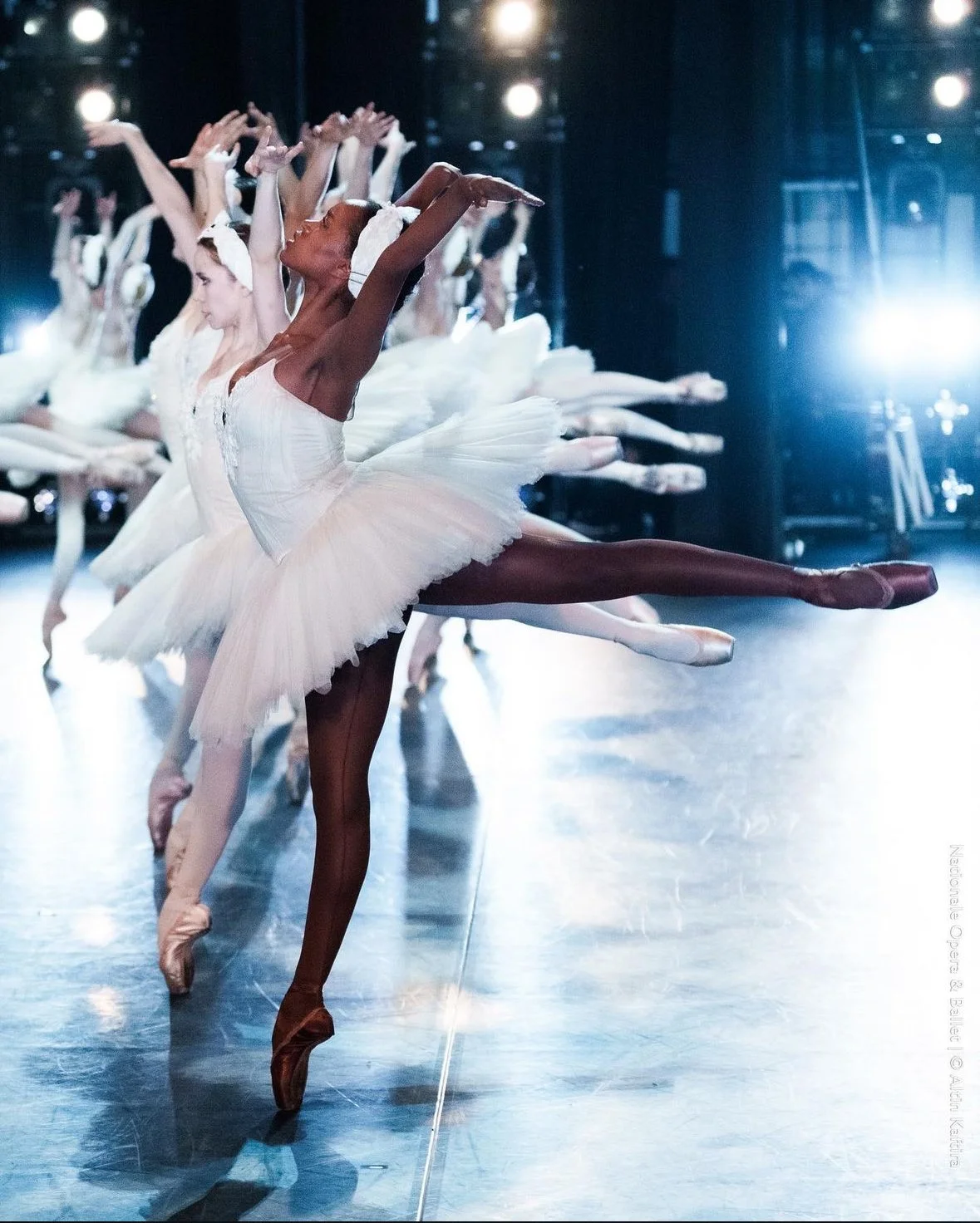 Ballet dancers practicing in a dance studio, dressed in white tutus and pointe shoes.