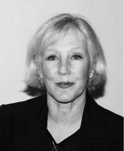 Black and white photo of a woman with shoulder-length hair, wearing a dark blazer.