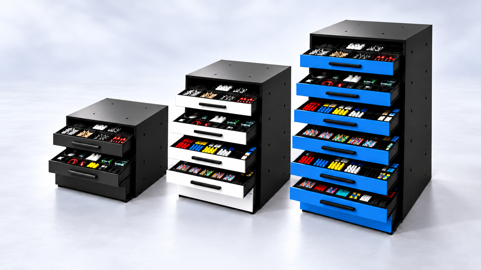 Three black storage units with multiple drawers containing colorful cables, connectors, and electronic components, arranged from smallest to largest, with the largest having blue drawers.
