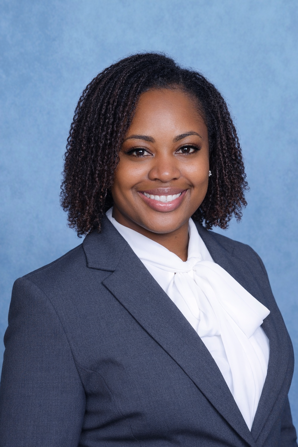 Professional portrait of a woman in business attire against a blue background.