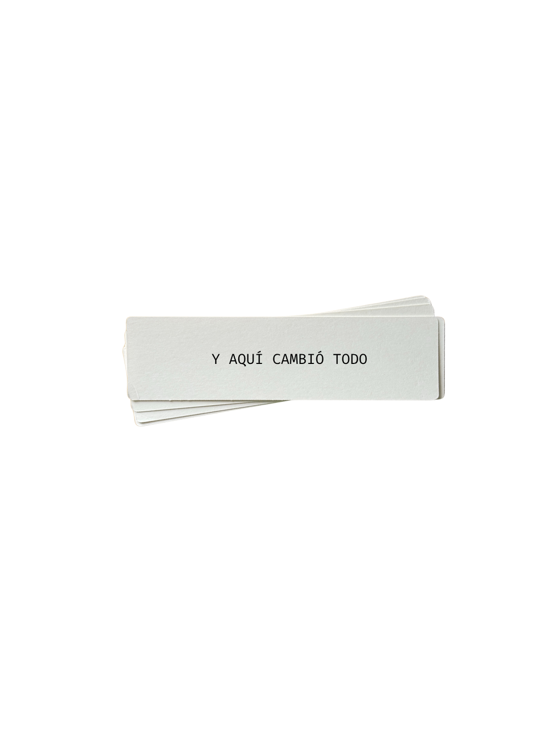 Biglietto di carta con la frase 'Y AQUÍ CAMBIÓ TODO' scritto sopra, ripiegato con altri fogli sottostanti.