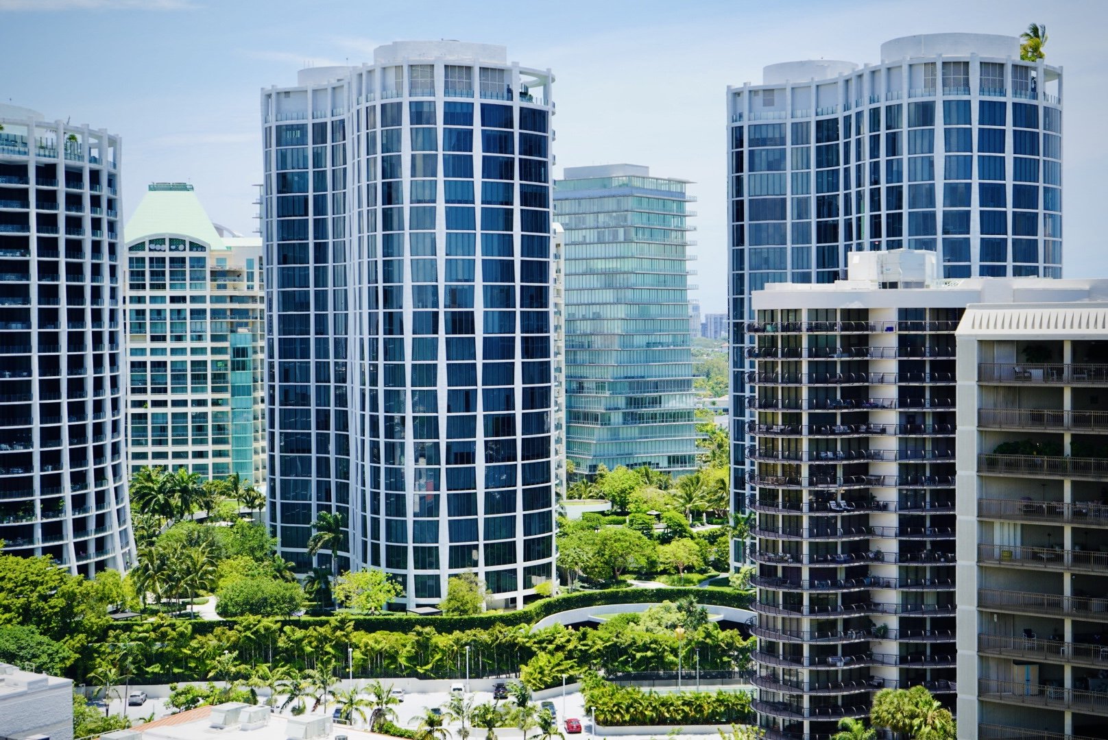 View of modern high-rise buildings with blue glass windows and green landscaping in a city.