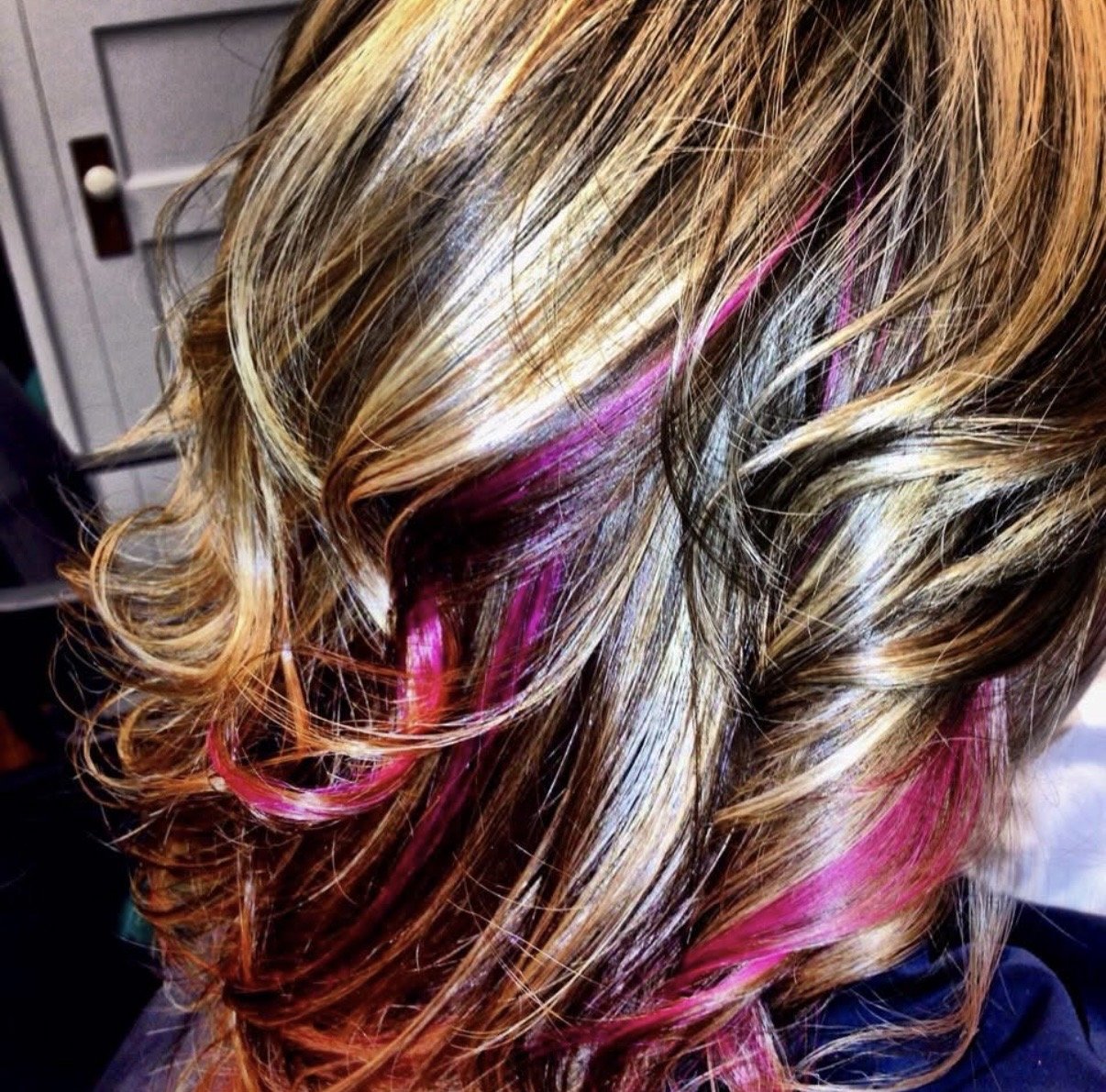 Close-up of styled, blonde hair with pink, purple, and orange streaks.