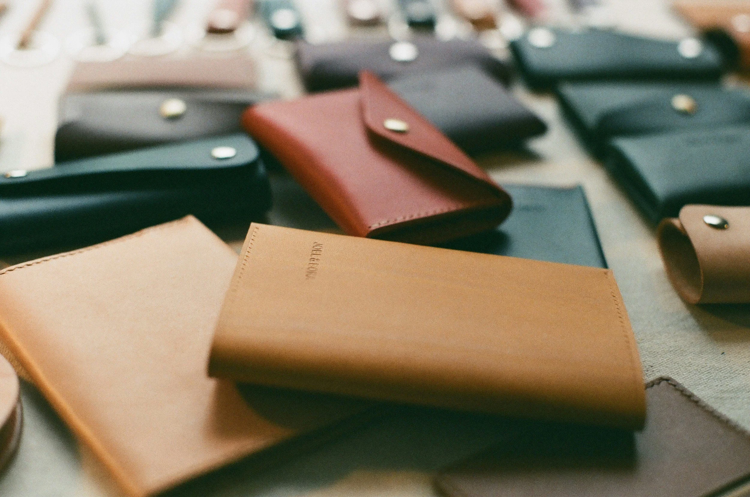 Close-up of various lightweight leather wallets in different colors, including black, red, tan, and green.