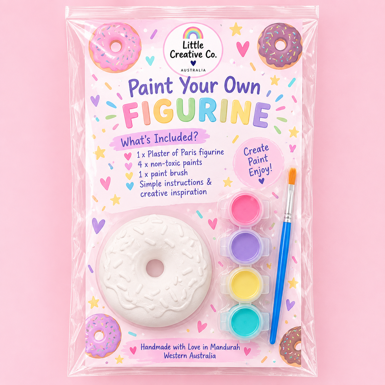 A crafting kit package titled "Paint Your Own Figurine" with colored paints, a paintbrush, a plaster donut figurine, and colorful decorative elements on a pink background.