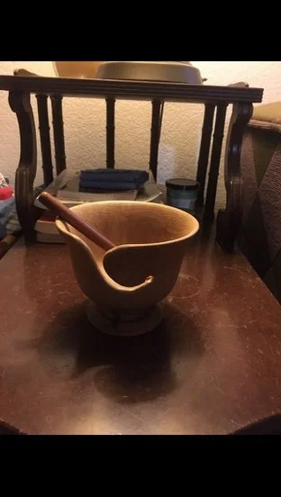 A ceramic mortar and pestle on a wooden table in a kitchen or dining area.