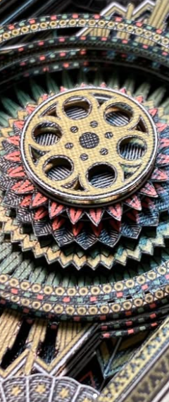 Close-up of a decorative, ornate wheel with multiple other circular patterns and colorful details surrounding it. Deck cuts. Cut decks. Kirigami. Playing card art