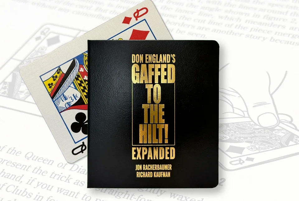 The image shows a black book titled 'Don England's Gaffed to the Hilt! Expanded' placed on top of two playing cards, the queen of diamonds and the queen of clubs, with a background of paper with written text and a faint illustration of a hand holding a card.