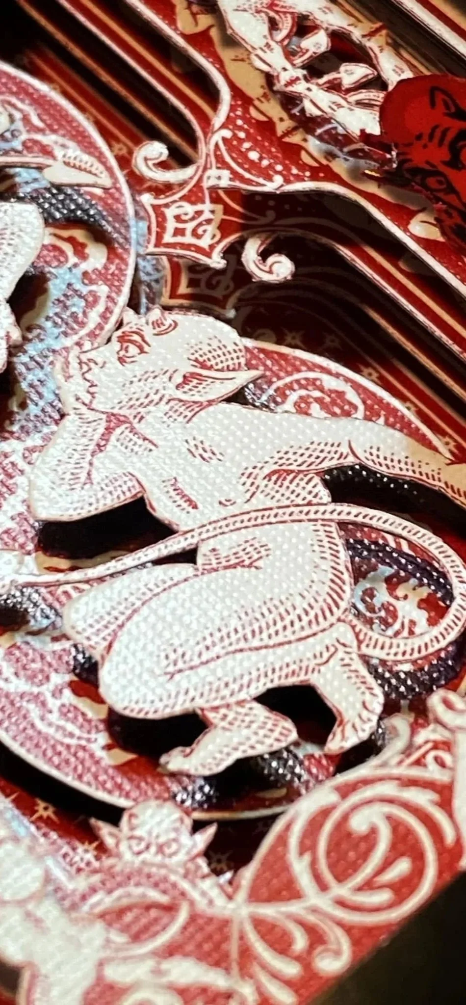 Close-up of a decorative paper cutout featuring a whispering imps deck of collectible playing cards. This is a deck cuts also referred to as cut decks. Playing card art
