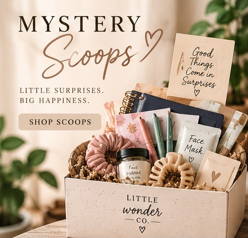 Display of gift boxes labeled 'Mystery Scoops' containing skincare and beauty products, including face masks, scrunchies, and notebooks, with a motivational card that reads 'Good things come in surprises'.