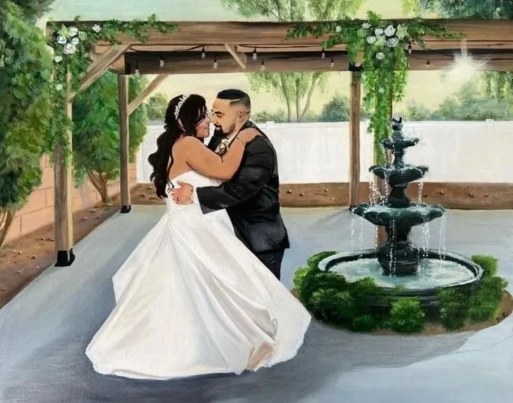 A bride and groom dancing under a wooden canopy with greenery, near a multi-tiered fountain at an outdoor wedding venue.