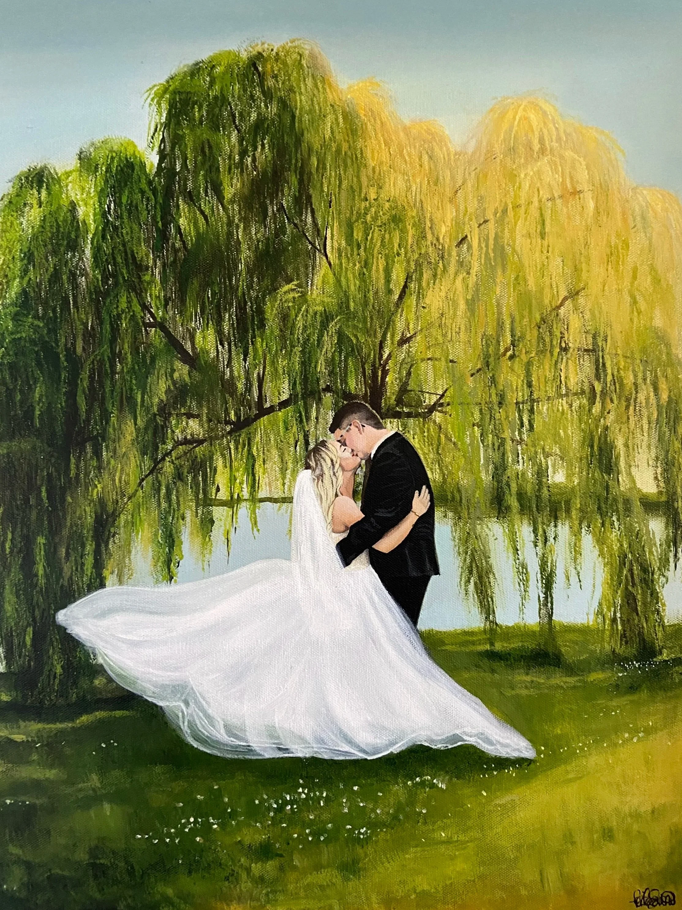 A couple in wedding attire kissing beneath a large weeping willow tree by a reflecting pond.
