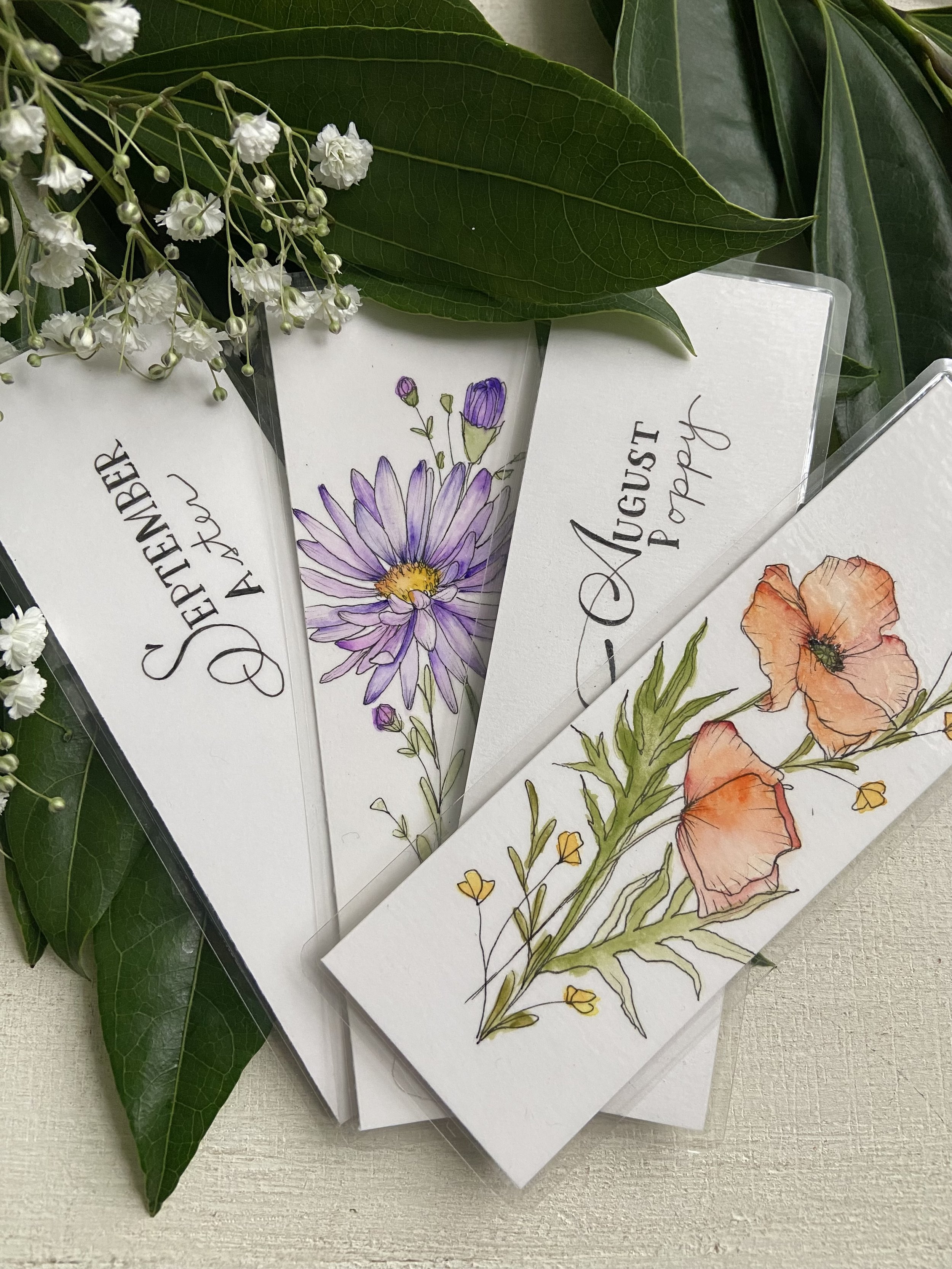 Set of four white cards with botanical and floral illustrations, titled 'September Autumn' and 'August Peach,' surrounded by green leaves and small white flowers.