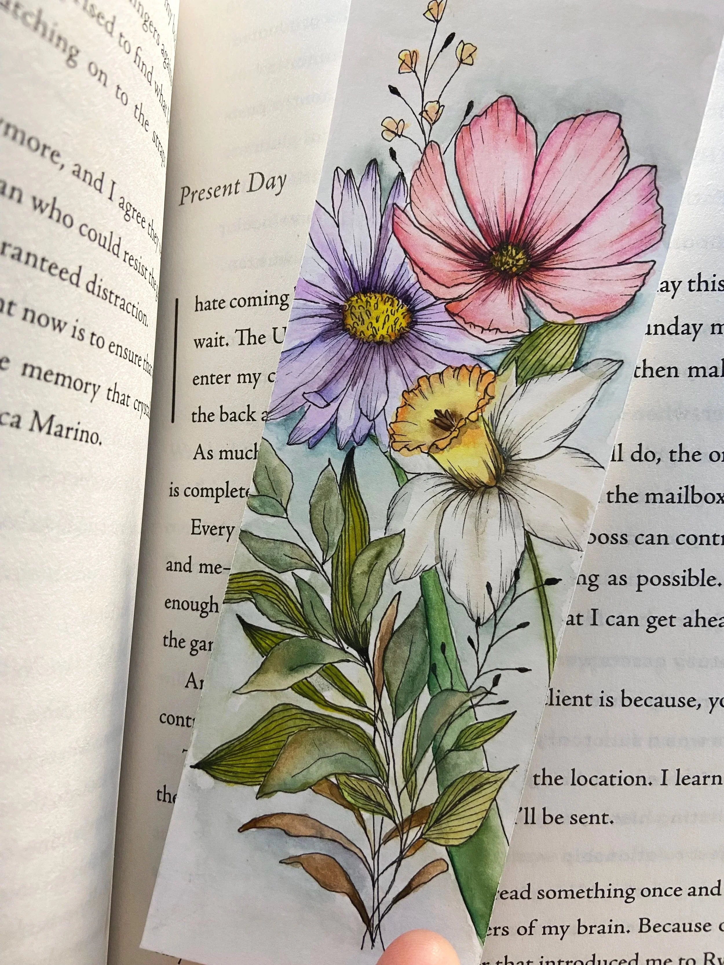 A hand-drawn illustration of various colorful flowers including pink, purple, yellow, and white blossoms with green leaves, overlapping pages of a book.