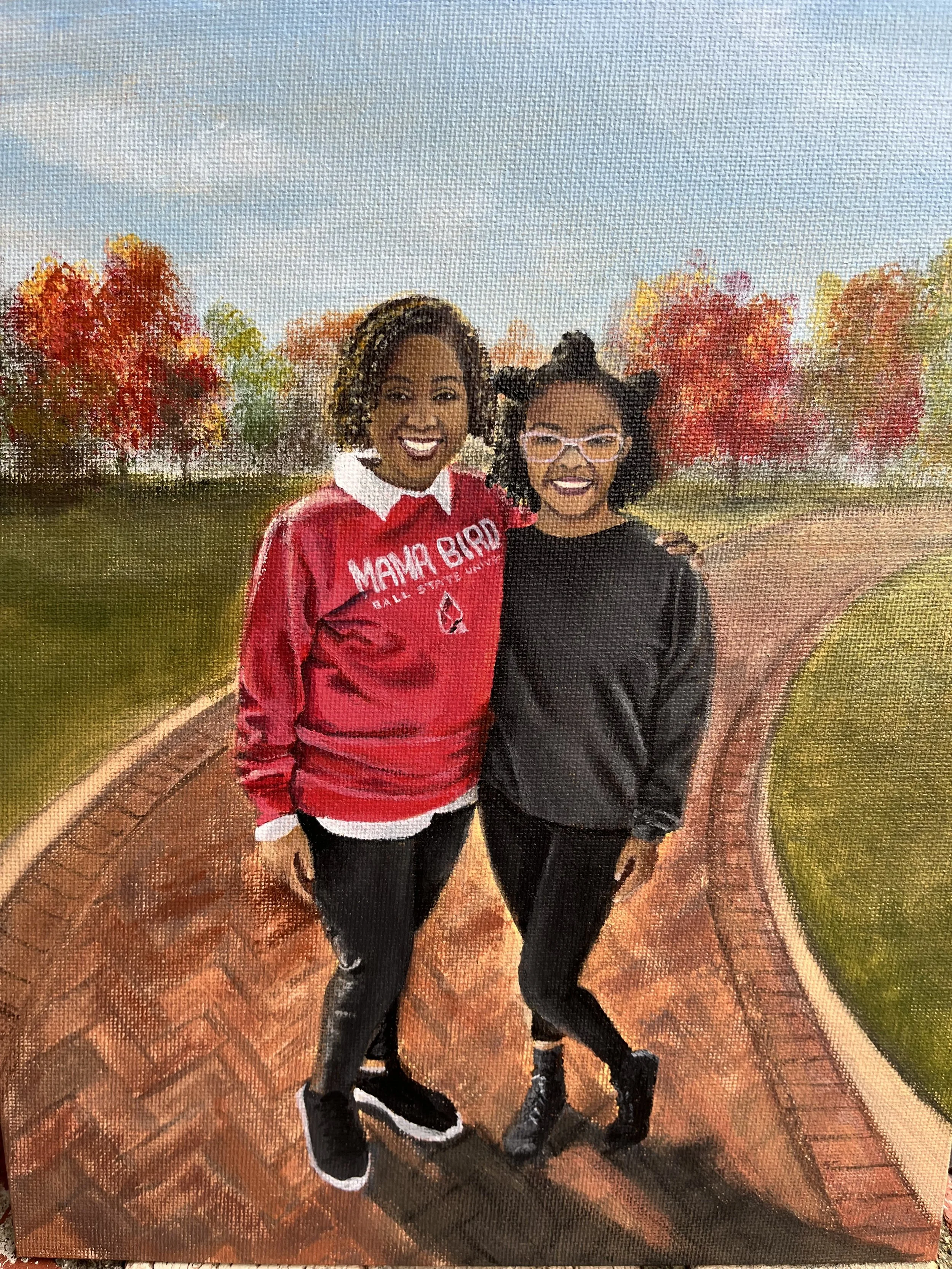 Two women standing together on a brick pathway with colorful autumn trees in the background.
