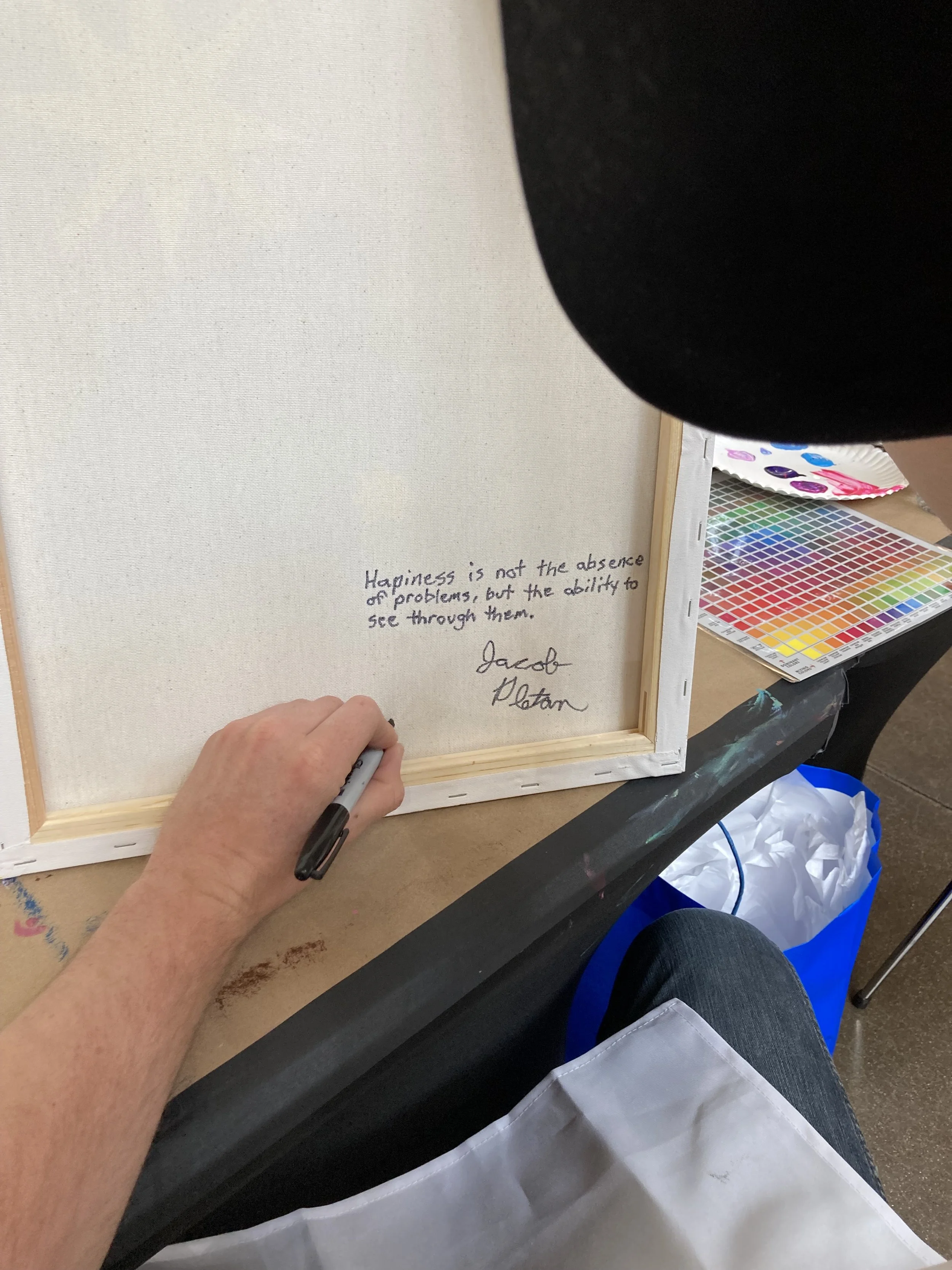 Person signing the quote, 'Happiness is not the absence of problems, but the ability to see through them,' at a workshop or event.